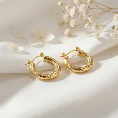 Textured Gold Bali Hoop Earrings with soft sunlight on satin background