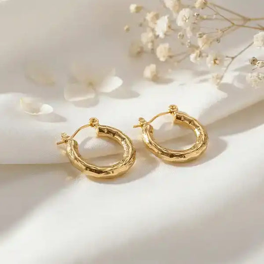 Textured Gold Bali Hoop Earrings with soft sunlight on satin background