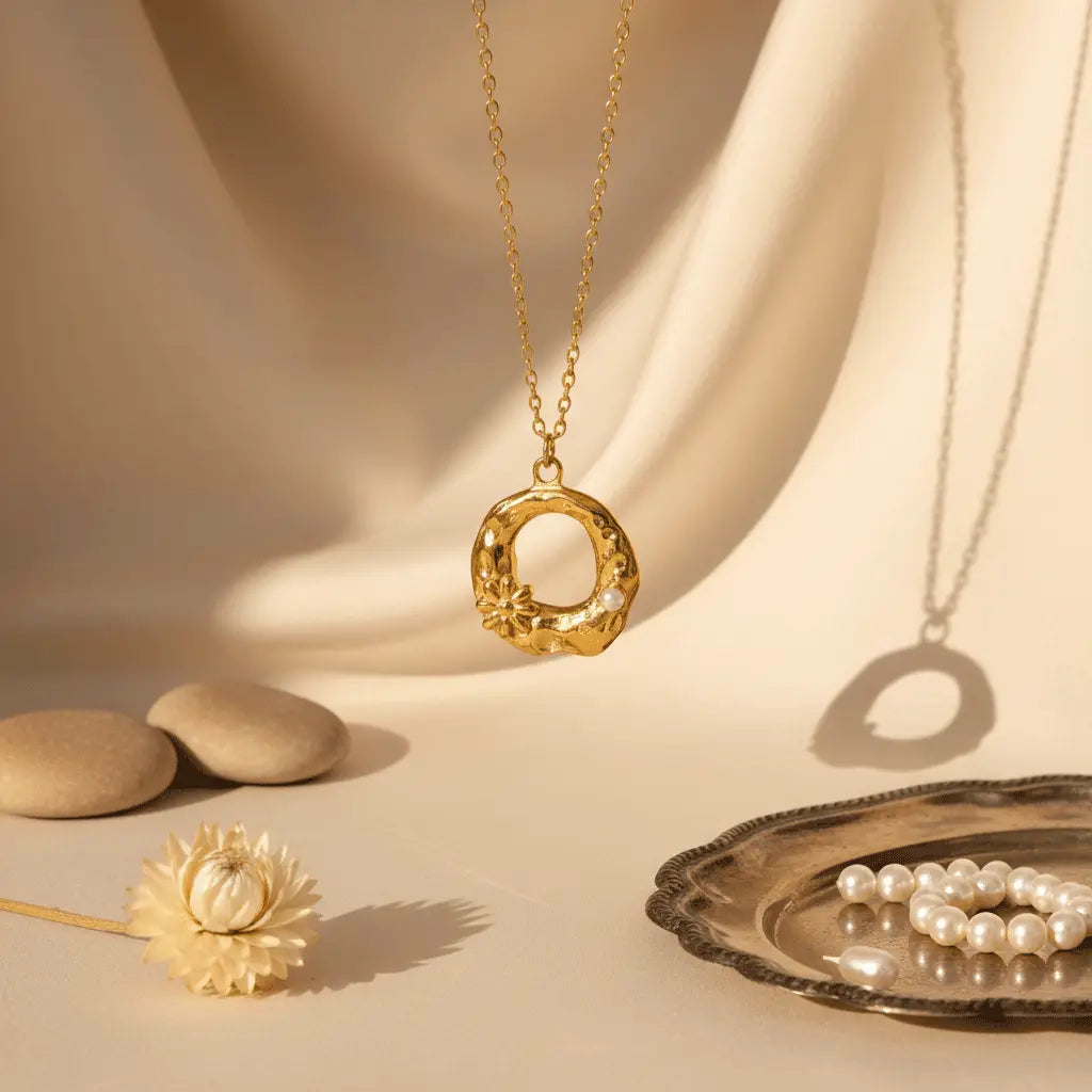 Textured round gold pendant necklace with floral detailing and pearls displayed on beige fabric with soft natural light.