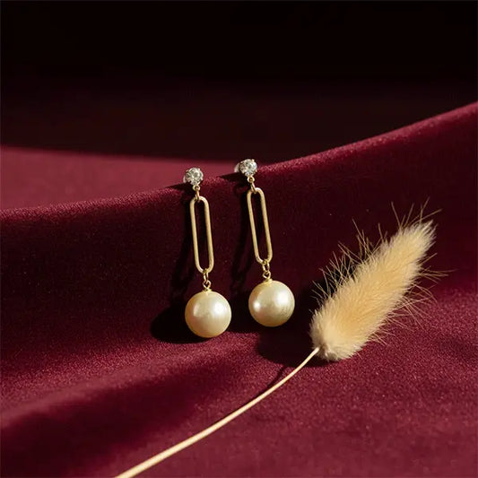 Timeless Pearl Drops earrings displayed on maroon velvet fabric with dried phalaris grass and soft studio lighting