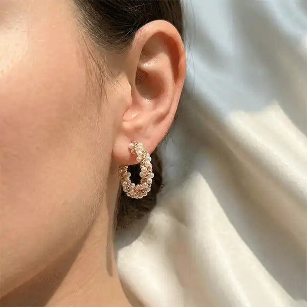 Twisted Pearl Hoops earrings worn on ear, gold hoop earrings with pearl detailing in soft natural sunlight