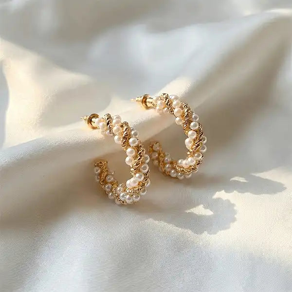 Twisted Pearl Hoops earrings worn on ear, gold hoop earrings with pearl detailing in soft natural sunlight