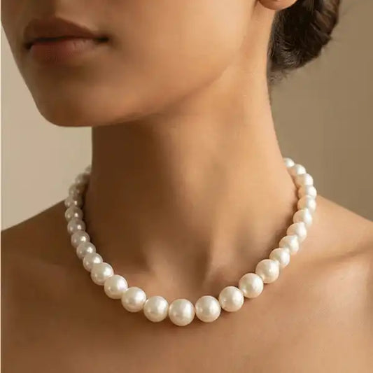 Classic round pearl necklace worn close to neck on model