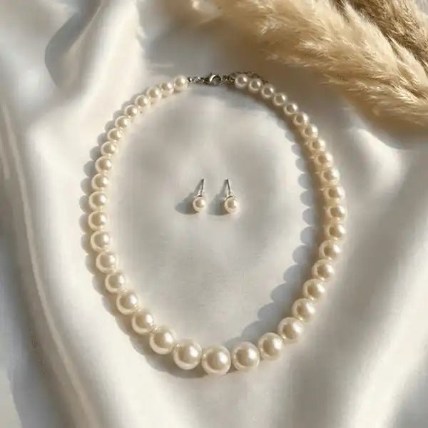 Round pearl necklace with matching pearl stud earrings on white satin