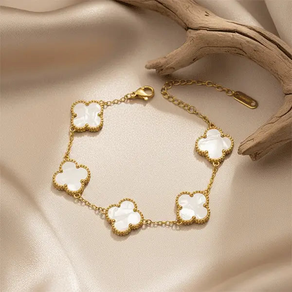 White Clover Bracelet with gold finish and white clover motifs placed on beige satin background, elegant anti-tarnish jewellery