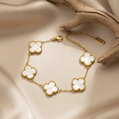 White Clover Bracelet with gold finish and white clover motifs placed on beige satin background, elegant anti-tarnish jewellery