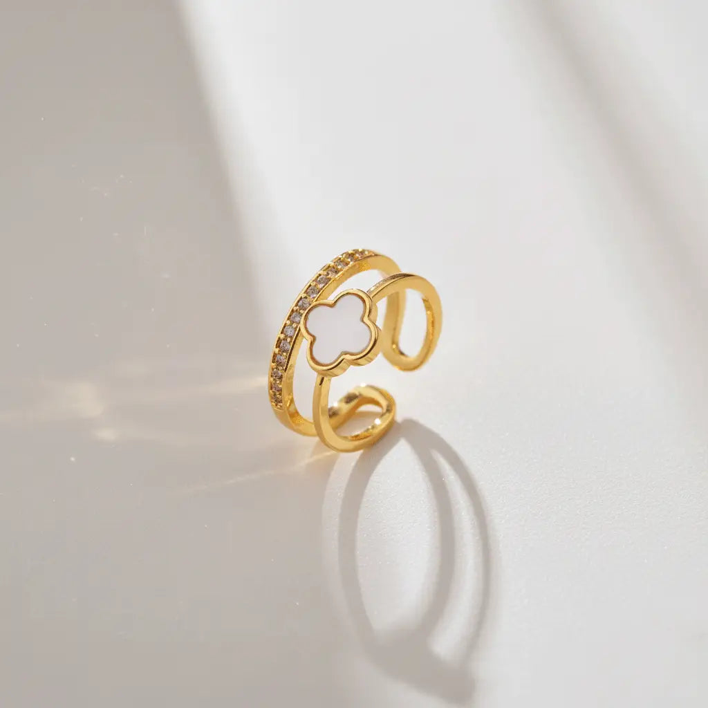 Gold White Clover Ring featuring a white clover charm and crystal-studded band showcased in natural sunlight.