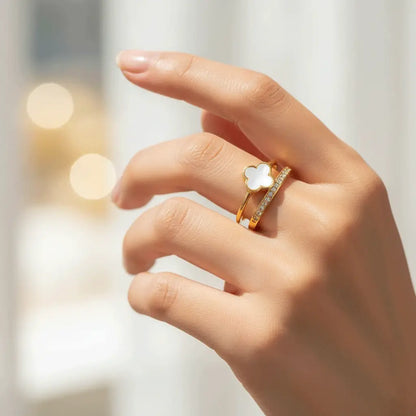 White Clover Ring with dual gold bands and crystals worn on hand against a softly lit background.